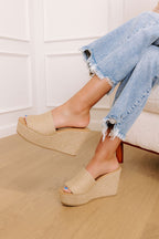 Tan jute wedge sandals with a wide woven strap and 4-inch heels, featuring a casual, bohemian style. 1