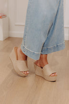 Tan jute wedge sandals with a wide woven strap and 4-inch heels, featuring a casual, bohemian style. 3